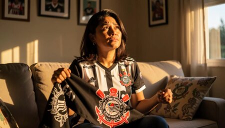 Torcedora corintiana emocionada segurando cachecol do Corinthians em casa